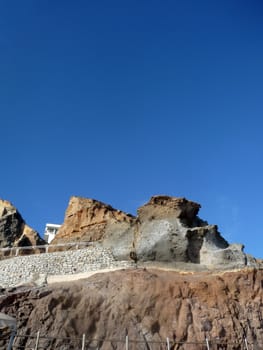 Some costal Cliffside rock against a blue sky.