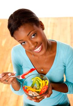 Beautiful attractive happy smiling health conscious young woman eating healthy salad from a bowl.