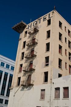 Wide shot of boarded up old urban hotel next to modern office building