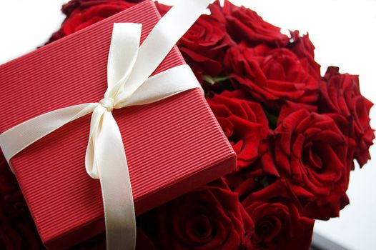 Gift box over red bunch of red roses