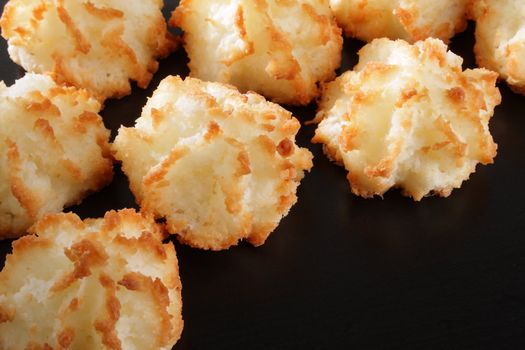 Group of coconut macaroons on dark wood.