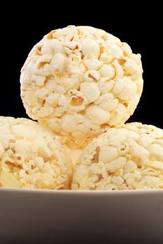 Bowl of several popcorn balls isolated on black.