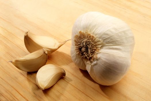 Garlic cloves displayed on a wooden cutting board.