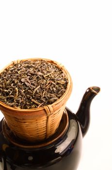 Green tea leaves in bamboo tea strainer on a tea pot.