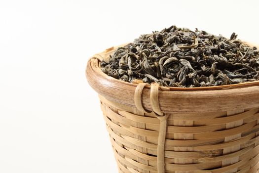 Green tea leaves in a bamboo tea strainer.