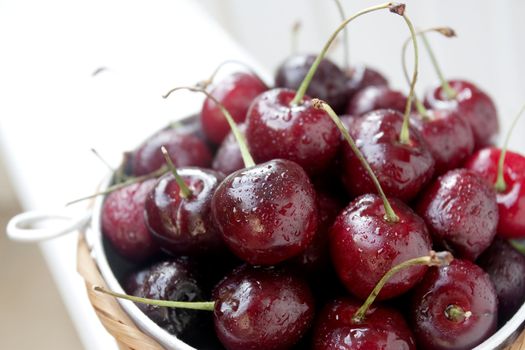 Wet ripe red sweet cherries in a bowl with limited focus.