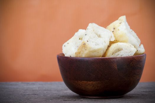 Croutons in a wooden bowl on a slate counter with copy space.