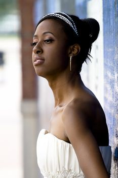 African American model wearing wedding gown posed against colorful wall.