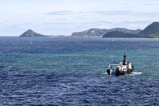 Boat traffic of the coast of beautiful St. Lucia with Pigeon Island in the distance, with copy space.