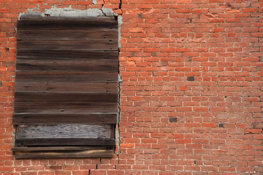 Old brick wall with weathered wood boarded window