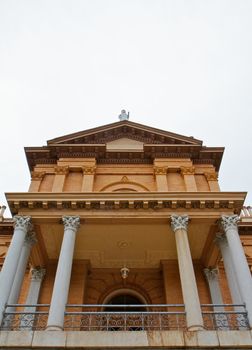 Front facade of pillared tan brick courthouse with statue on top