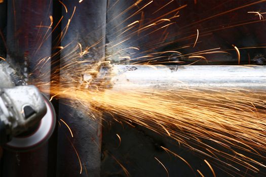 man grinding steel at night with a disk grinder 