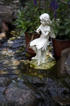 Water nymph statue playing the flute by a stream