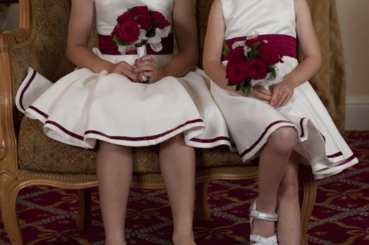 two young bridemaids with bunches of red flowers