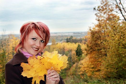 Young pretty woman with yellow leaves in hands