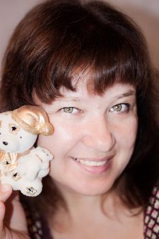 Adult smiling woman with small toy Teddy Bear in hand