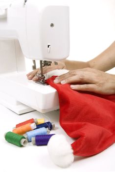 woman sewing a hat for Santa Claus on the sewing machine