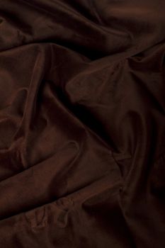 Close up view of a wrinkled dark brown silk fabric background.