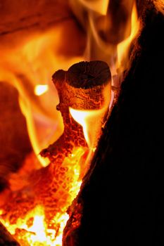 Close view of a wood log being burned in red hot flames.