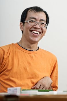Happy smiling Asian man play Mahjong, traditional Chinese game.