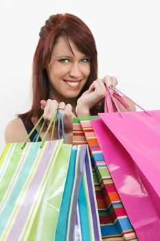 A beautiful redhead girl holding shopping bags and smiling.