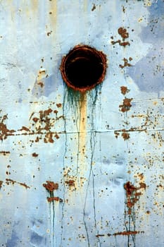 View of an old and rusty section of a blue ship on the docks.