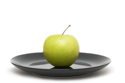 Green apple on a black plate