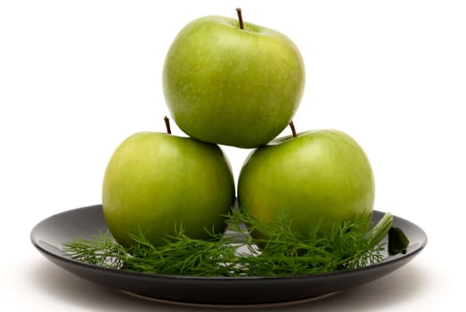 Three apples with dill on a black plate