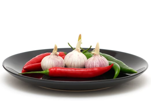 Three garlics with chili peppers on a plate