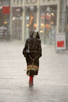 A womman is walking alone in the rain. Blury because of the rain.