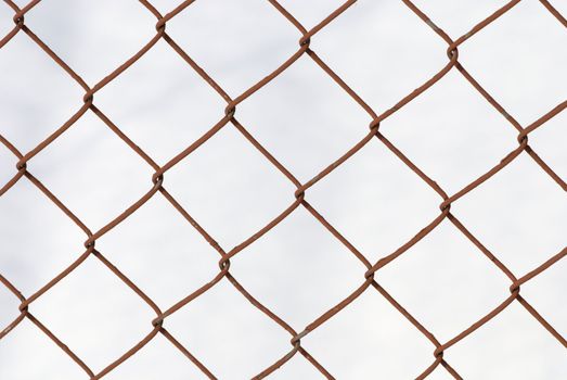 Knotted grid like chain-link fence against cloudy sky