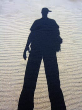 Shadow of a man reflected on the sand.