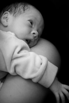 Newborn on mothers shoulder in black and white