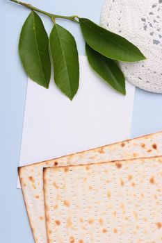 A white kippah and matzah next to a piece of white paper. Add your text to the paper.