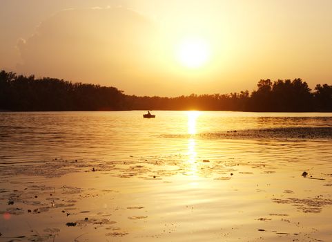 Silhouette of a fisherman on the river at sunset