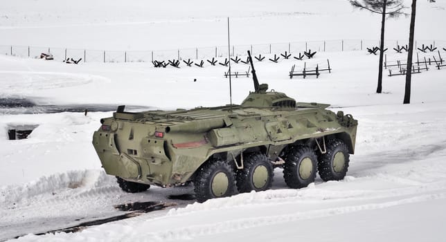 The green armoured troop-carrier goes on winter road