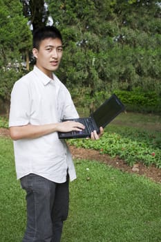 Young man use a notebook in park at day
