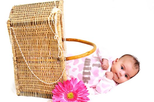 baby girl laying in a brown basket, white beads and big pink flower
