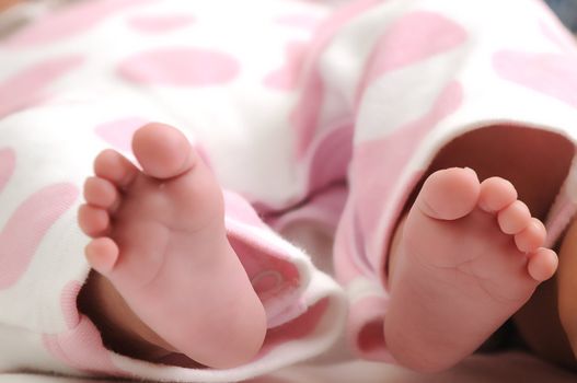 close-up photo of sweet baby girl wearing pink dotted clothes and her feet sticking out