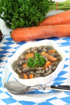 a bowl of soup with liver dumplings carrots and parsley