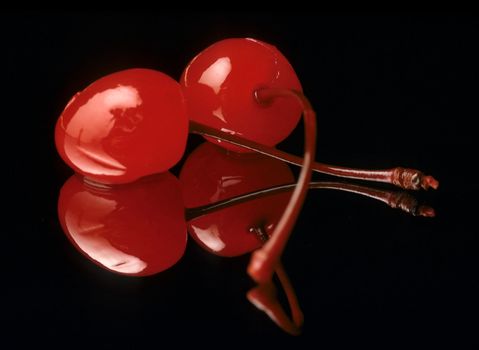 red maraschino cherries on black with reflection