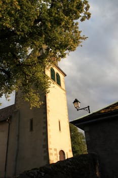Side of the bell tower of a small church by sunset