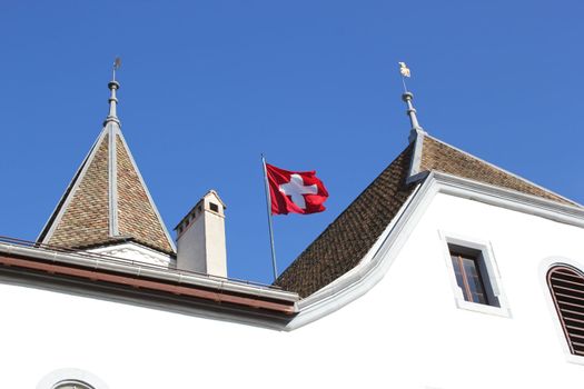 Swiss flag floating upon the roof of Nyon castle, Switzerland