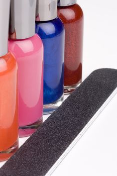 Different colored nail polish bottles next to a nail file.