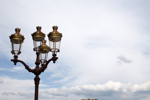 A beautiful french classic style streetlight on a cloudy summer sky.