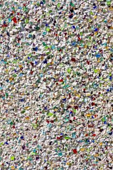 Close view of a textured wall with broken glass of various colors.