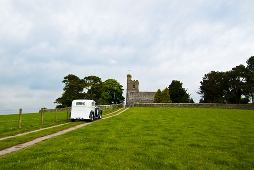 vintage wedding car approaching small rural church