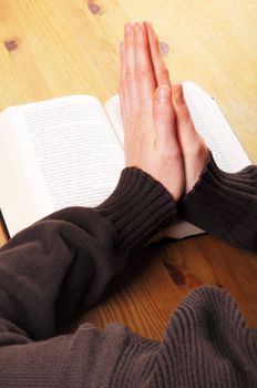 praying hand and book on desk showing religion concept