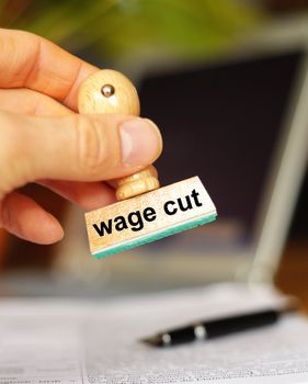 wage cut concept with stamp in office or bureau showing financial crisis