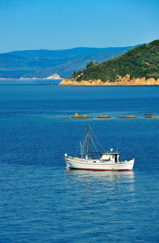 White fishing trawler anchored among islands of the Aegean Sea